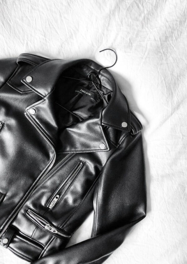black leather jacket laying on bed