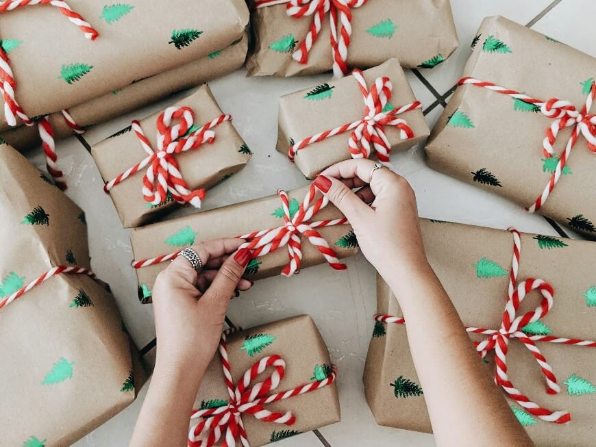 woman wrapping christmas presents with red nail polish