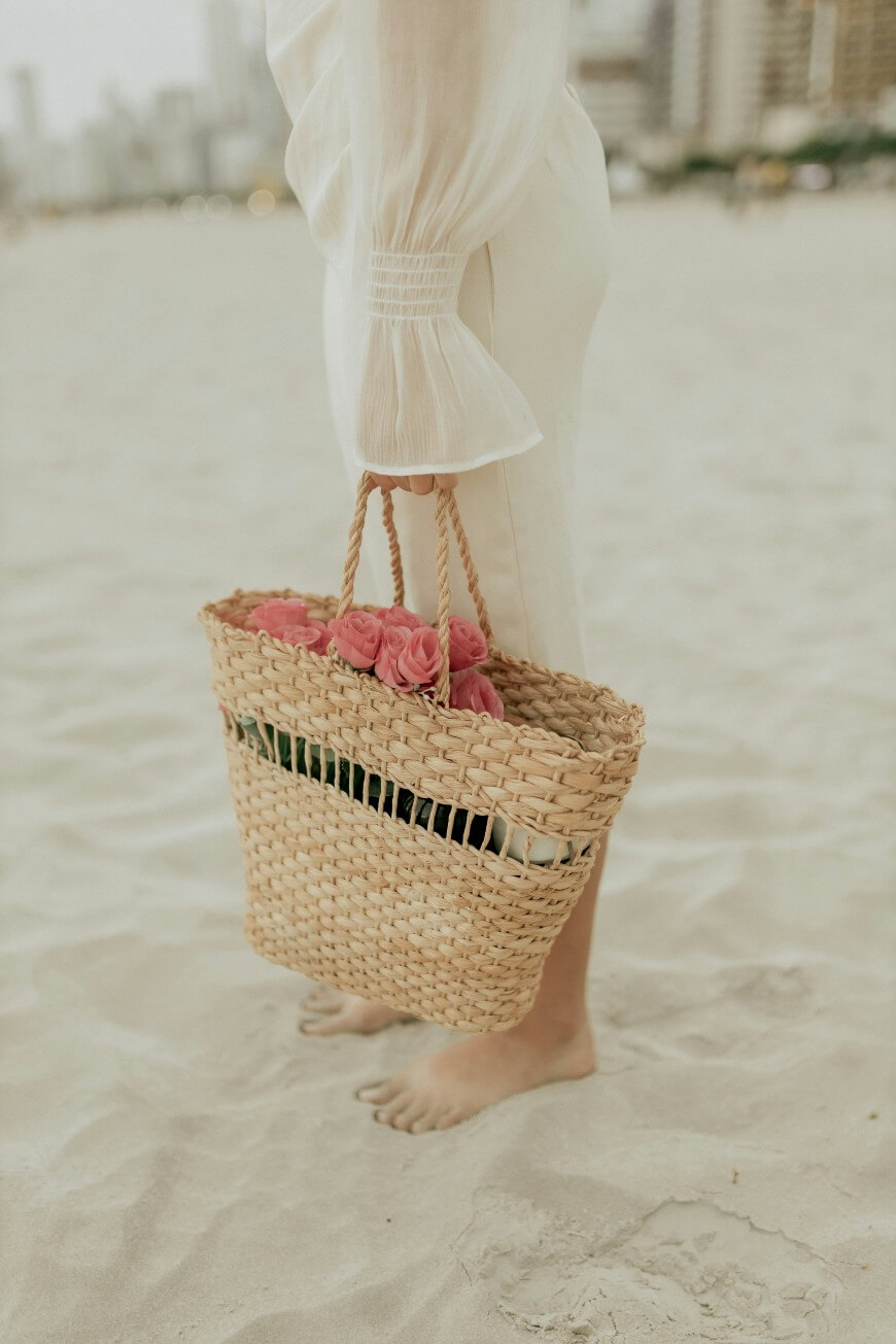 woman on beach with straw bag