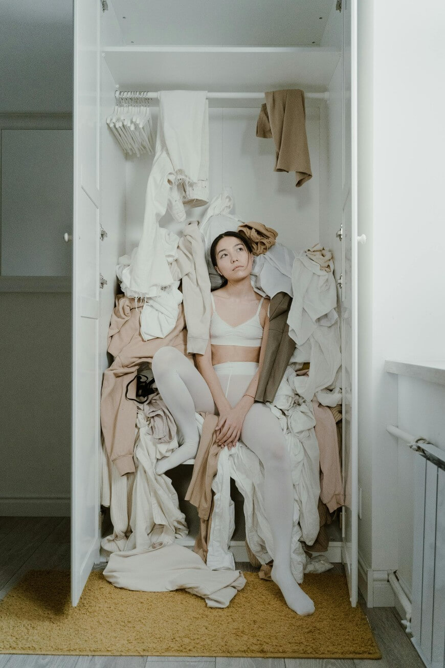 woman surrounded by her own clothes