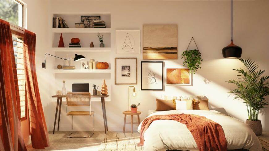 Cozy bedroom with a neatly made bed, rust-colored blanket, a laptop on a wooden desk, wall shelves with books and decor, potted plants, and warm natural light from large windows with rust curtains.
