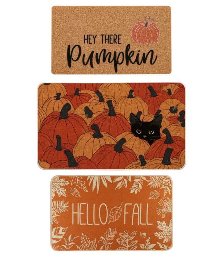 Three autumn-themed doormats: one says Hey There Pumpkin with a pumpkin graphic, one features a black cat hiding among pumpkins, and one says Hello Fall with white leaves on an orange background.