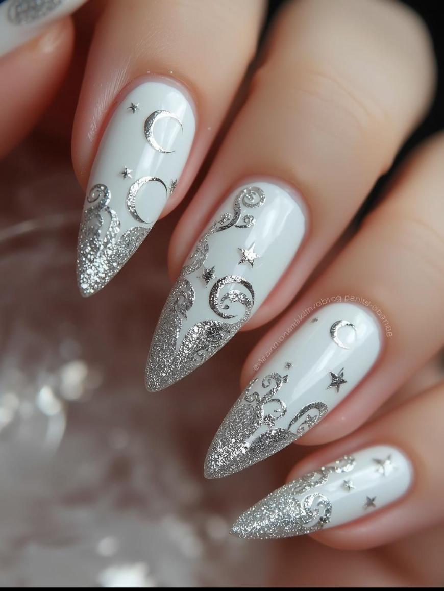 A hand with long, pointed nails painted white, featuring silver glitter tips and intricate moon and star designs in silver, creating an elegant celestial theme.