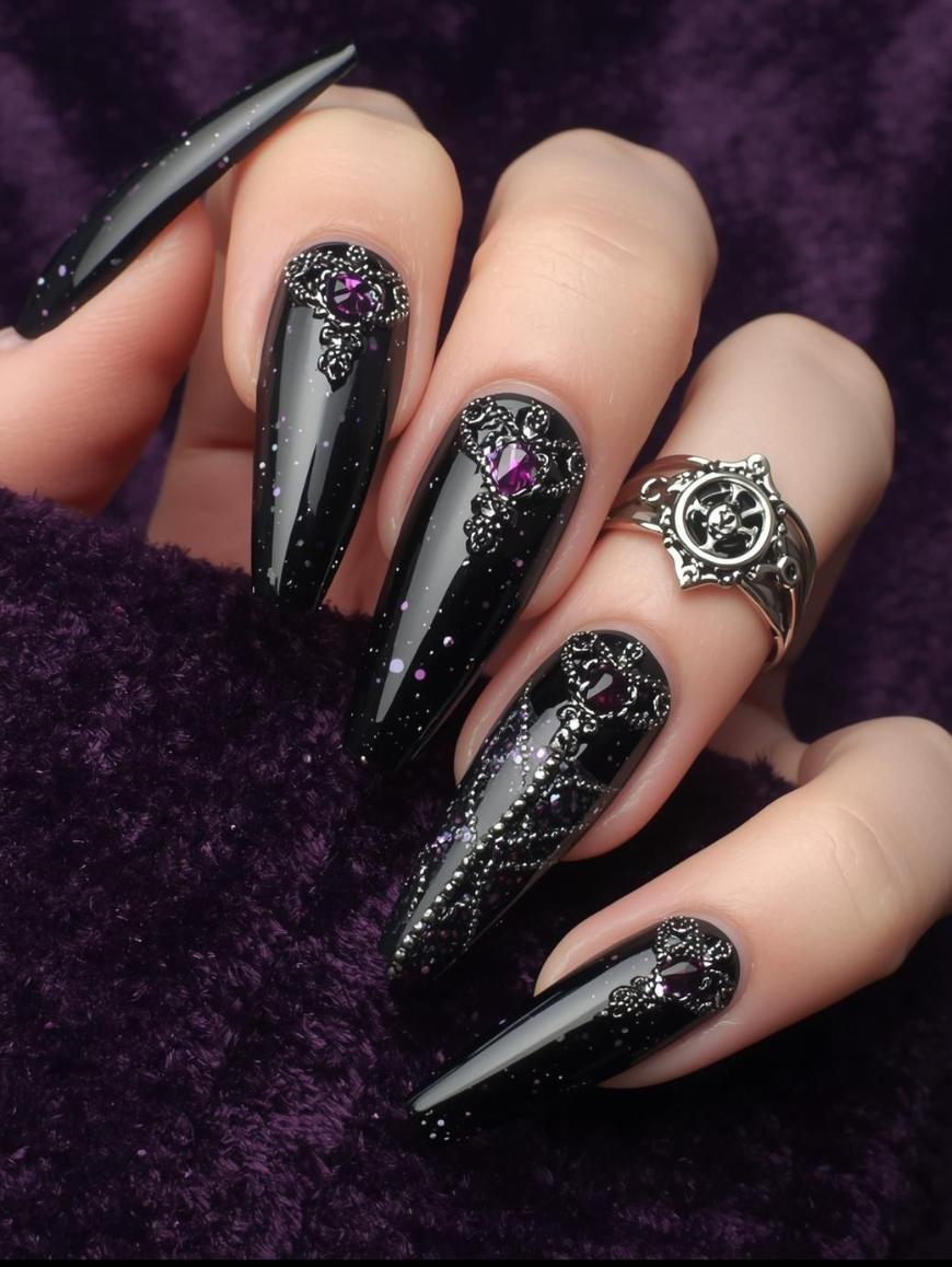 A hand with long, pointed black nails featuring intricate silver designs and purple gemstones, holding a dark purple velvet fabric. The hand wears a silver ring with an ornate design.