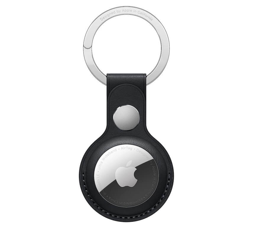 A black leather keychain holder with a circular Apple AirTag inside, featuring a silver ring at the top for attaching keys. The AirTag displays the Apple logo and engraved text around its edge.