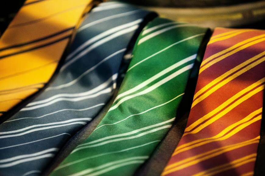 Four neckties with diagonal stripes in yellow, blue, green, and red colors, each featuring a distinct stripe pattern, are laid out side by side.