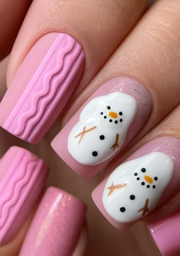 Close-up of manicured nails with a pink base. Some nails feature 3D wavy designs, while others display cute hand-painted snowmen with orange noses, black eyes and buttons, and brown stick arms.