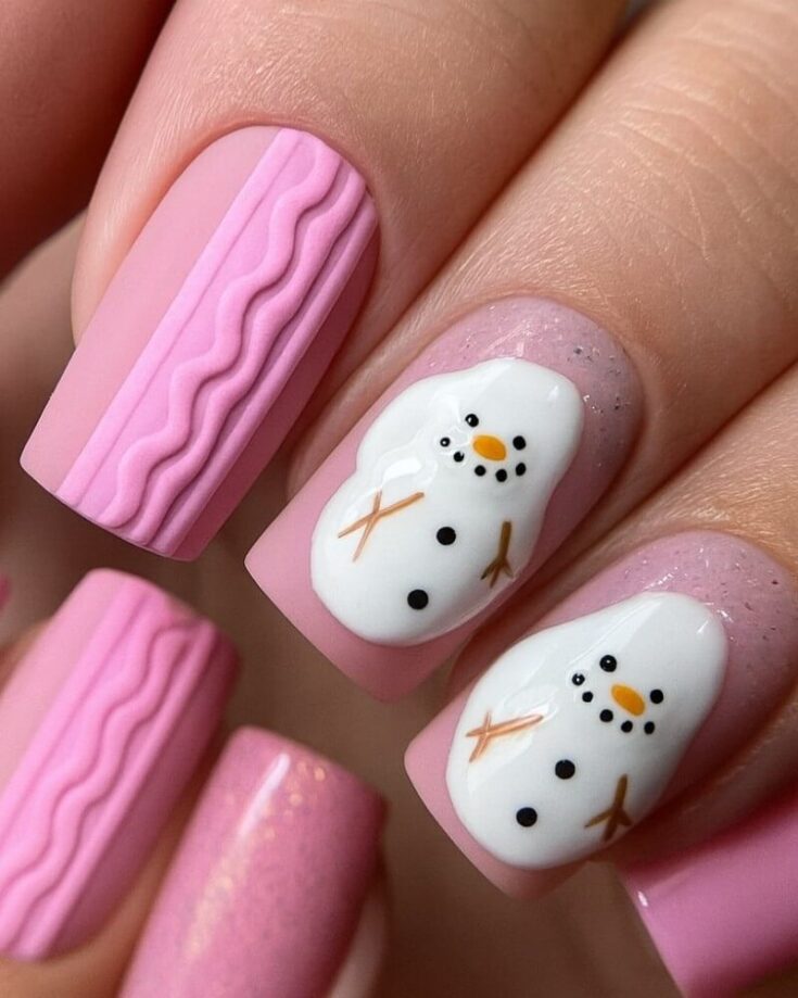 Close-up of manicured nails with a pink base. Some nails feature 3D wavy designs, while others display cute hand-painted snowmen with orange noses, black eyes and buttons, and brown stick arms.
