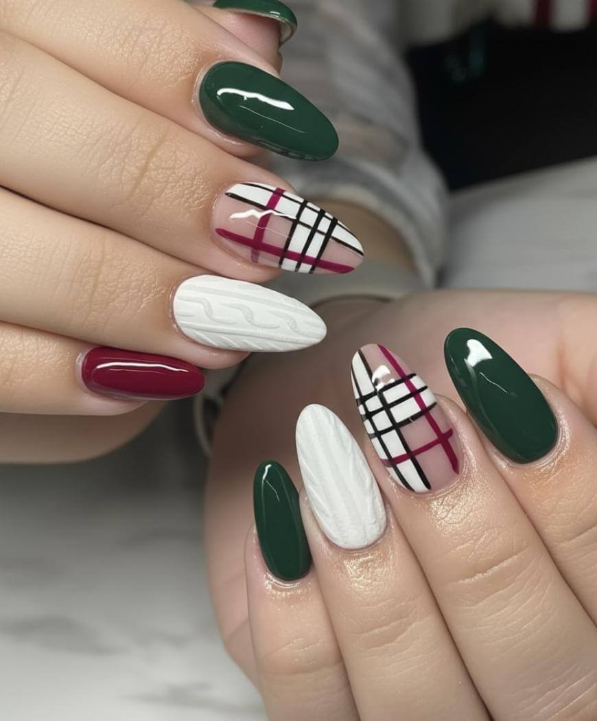 Close-up of hands with manicured nails featuring dark green, burgundy, and white polish, plaid patterns in black and red, and a white cable-knit textured design on some nails.
