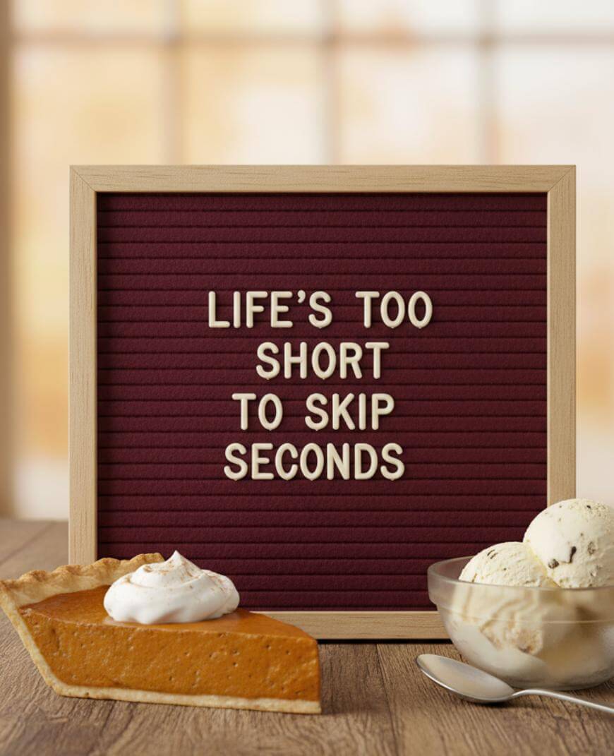 A letter board with the message LIFES TOO SHORT TO SKIP SECONDS sits behind a slice of pumpkin pie with whipped cream and a bowl of vanilla ice cream on a wooden table.