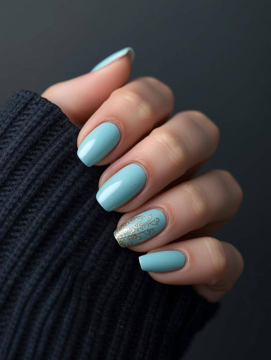 A hand with neatly manicured nails painted light blue; the ring fingernail features a gold floral design. The person is wearing a dark, ribbed sweater.