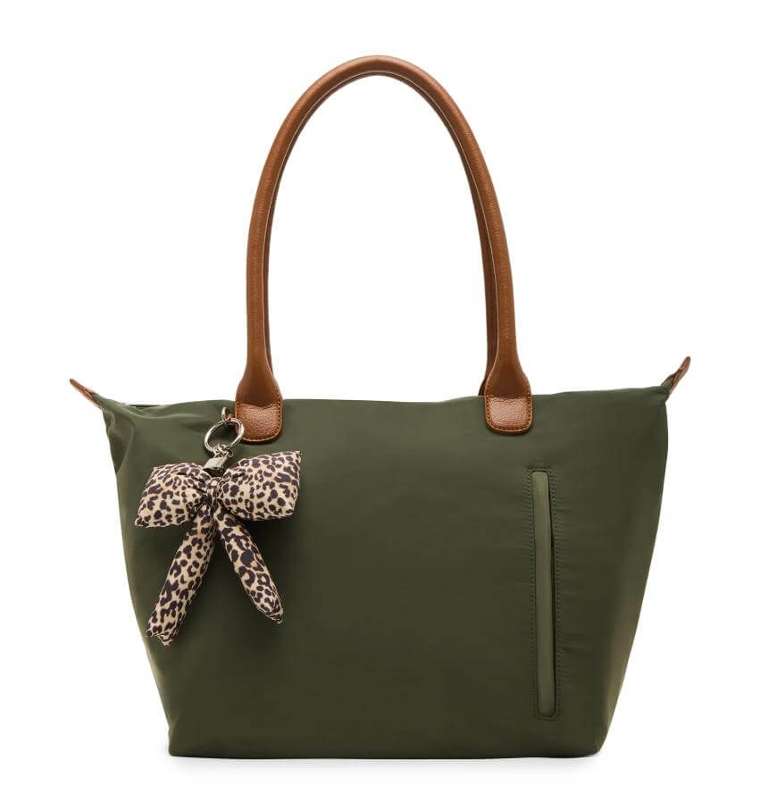 A green tote bag with brown leather handles, a front zippered pocket, and a keychain featuring a leopard print bow attached to one handle.