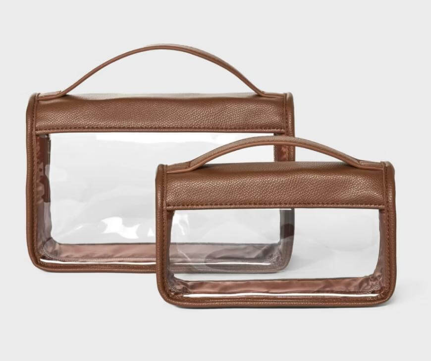 Two brown toiletry bags with clear plastic panels and matching handles, one larger and one smaller, are displayed on a plain light background.