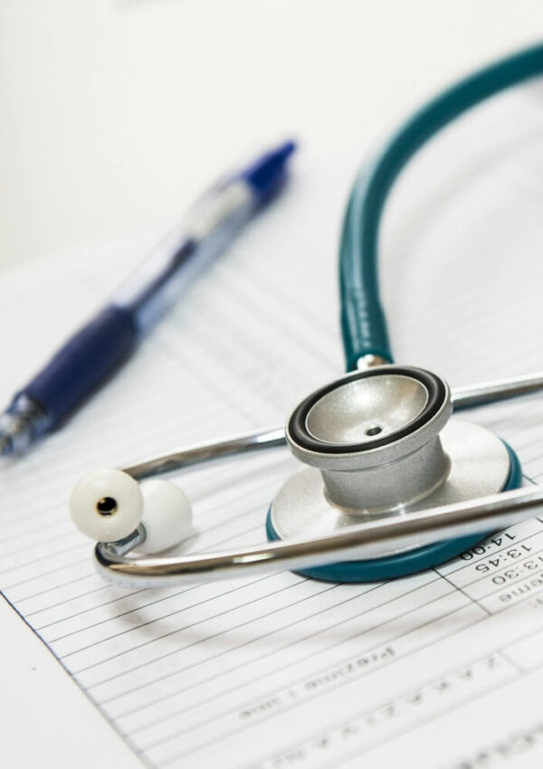 A stethoscope rests on a medical chart with a pen nearby, suggesting a healthcare or medical examination setting.