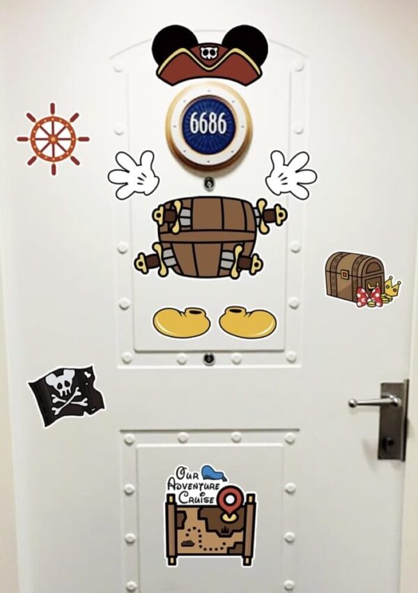 A white door decorated with nautical and pirate-themed stickers, including a ships wheel, treasure chest, pirate flag, and a round plaque with the number 6686. Mickey Mouse’s hat, gloves, and shoes are also featured.