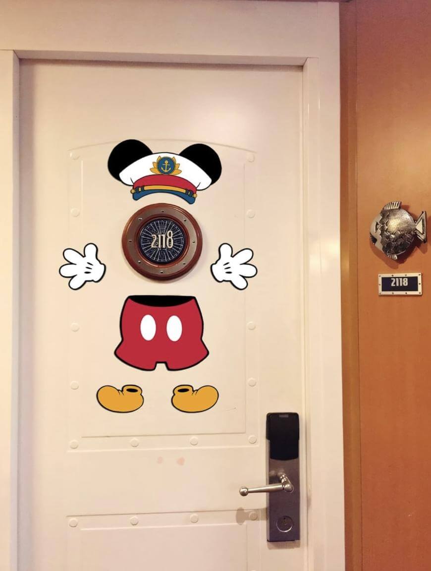 A white door decorated with a cartoon captain Mickey Mouse body, with the room number 2118 as Mickey’s face. A fish plaque with the same number is on the wall beside the door.