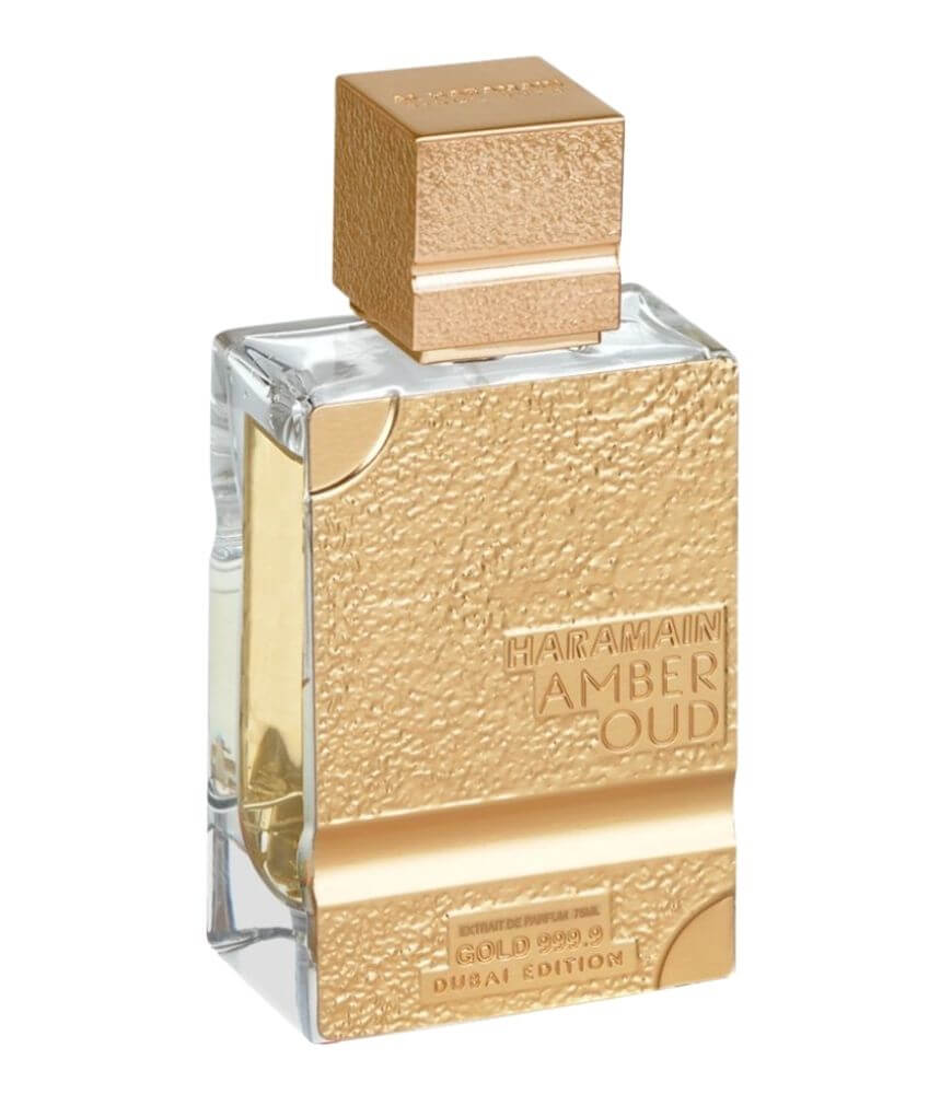 A rectangular perfume bottle with a textured gold front and cap, labeled Haramain Amber Oud Gold Edition Dubai Edition. The bottle contains a light yellow liquid.