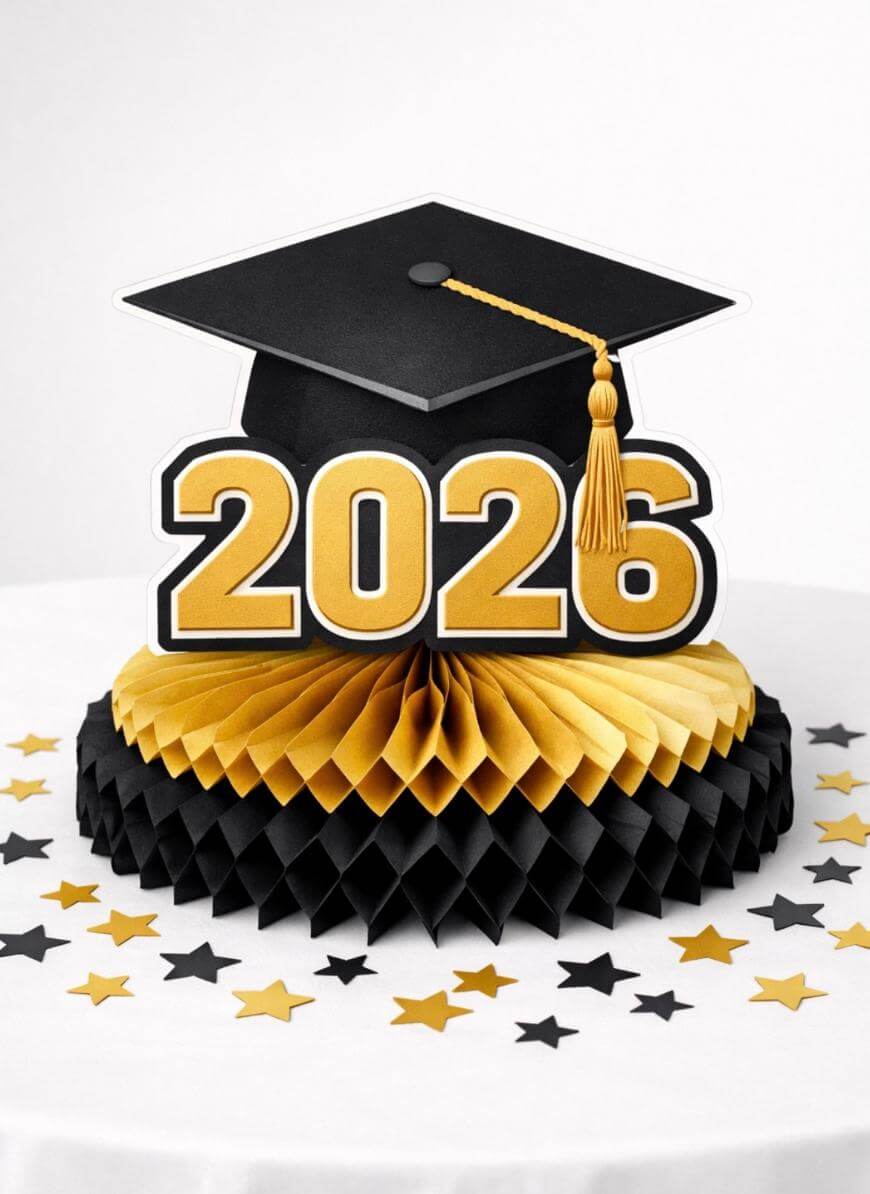 A graduation centerpiece features a black cap with a gold tassel and large gold numbers 2026 on a honeycomb base, surrounded by black and gold star confetti on a white surface.