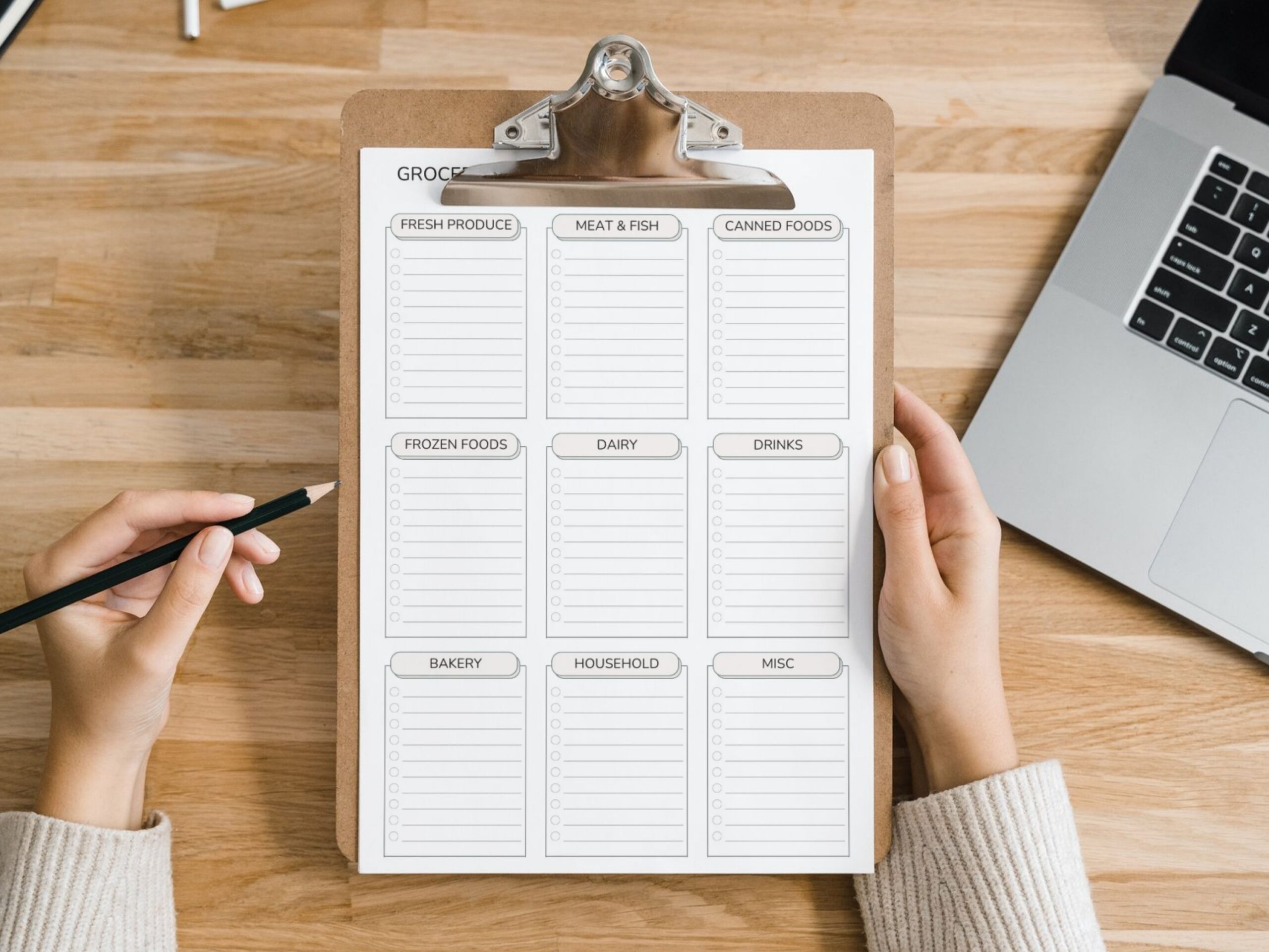 A person holds the Minimalist Grocery Shopping List Printable PDF – Categorised Weekly Checklist (A4, A5, Letter & Half Size) on a clipboard, featuring blank sections for fresh produce, dairy, bakery, meat & fish, and household items.