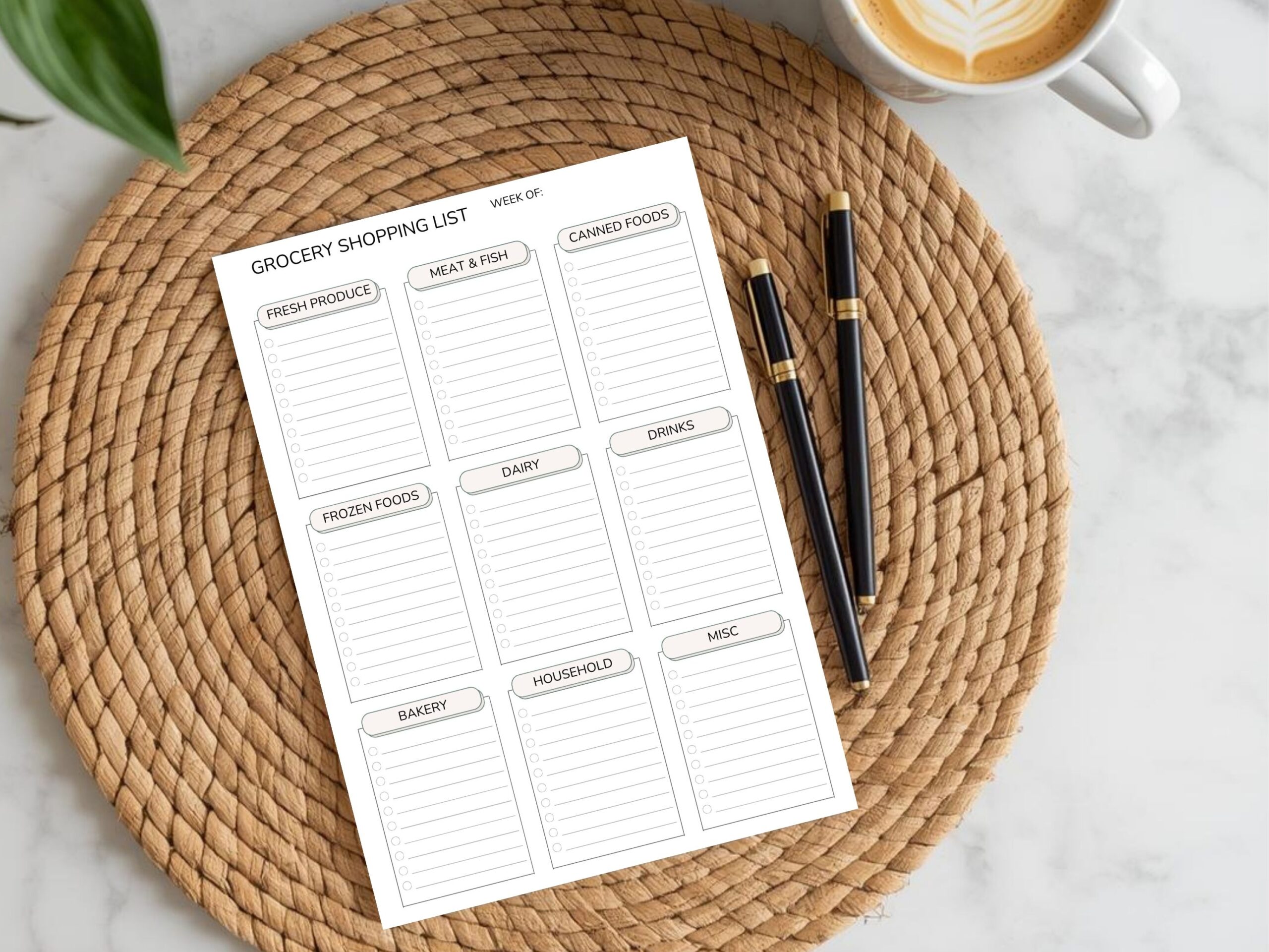The Minimalist Grocery Shopping List Printable PDF – Categorised Weekly Checklist (A4, A5, Letter & Half Size) sits on a woven placemat with pens and coffee nearby—ideal for organising your weekly shopping.