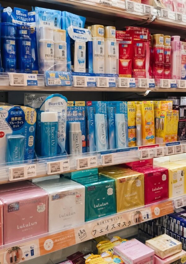 Shelves stocked with various Japanese skincare and beauty products, including facial masks, sunscreens, and boxed sets in colorful packaging; a must-see for any Japan shopping guide, with product labels and price tags visible.