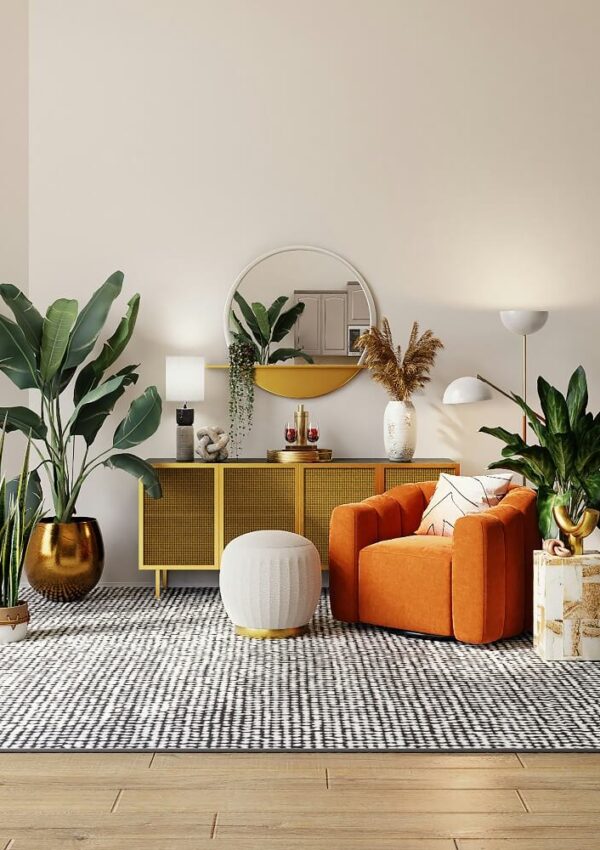 A modern living room with an orange armchair, a white pouf, a gold sideboard, large green plants, a round mirror, floor and table lamps, decorative vases, and a patterned gray rug on a wooden floor.