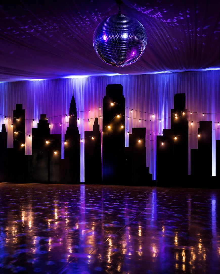A disco ball hangs above a dance floor with city skyline silhouettes and string lights, all illuminated by purple and blue lighting.