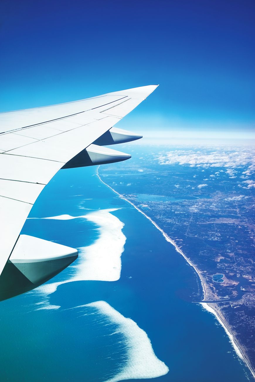Airplane wing view over coastline representing NovaJet private family air travel
