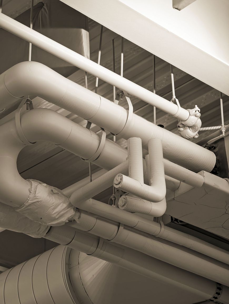 Exposed insulated pipes and ducts run along a ceiling, revealing a network of industrial or commercial HVAC infrastructure that could easily display signs of dirty air ducts often found in Charleston homes.
