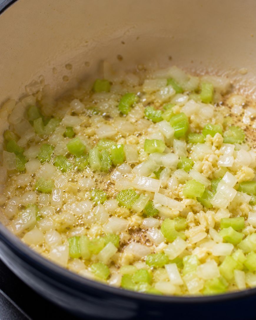 Diced onion, celery, and garlic sauteing in a pot.