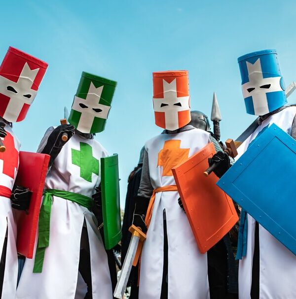 Four friends dressed as color-coded knights, each in a different colored tunic and mask, for a group Halloween costume.