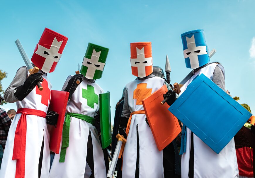 Four friends dressed as color-coded knights, each in a different colored tunic and mask, for a group Halloween costume.