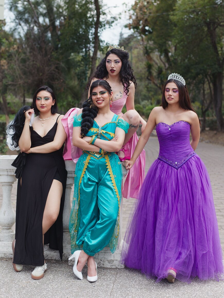 Four women in colorful fairytale-inspired gowns and tiaras for a group Halloween costume.