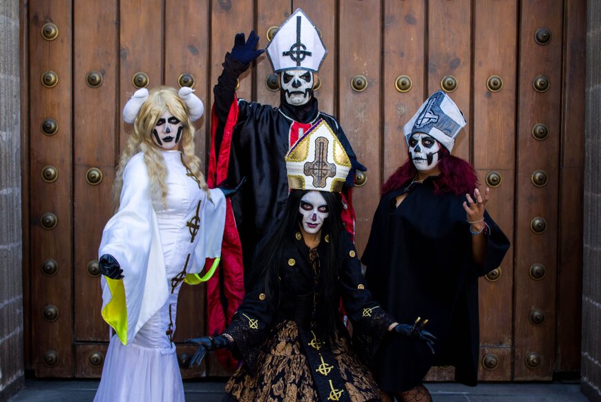 Four people in dramatic black and white gothic costumes with skull face paint for a group Halloween look.