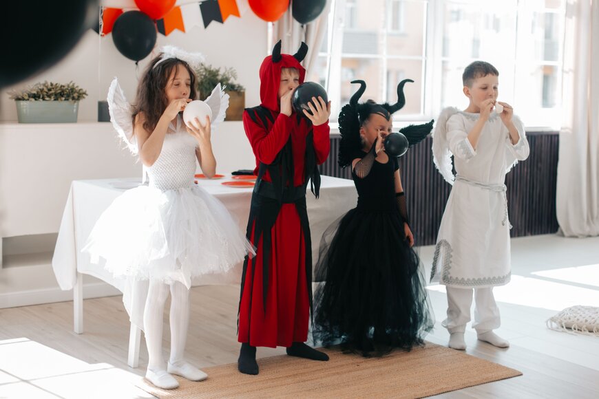 Four children dressed as angels and devils for a family-friendly group Halloween costume.