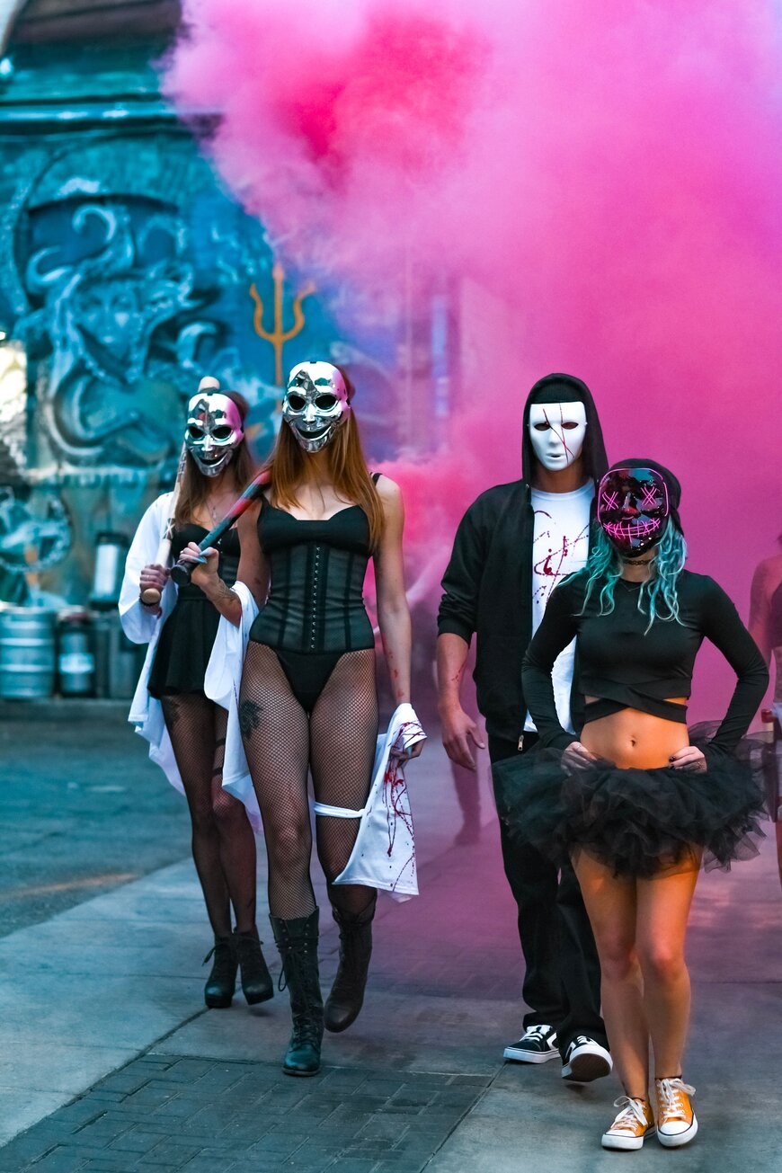 Four friends in matching black outfits and masks for a coordinated group Halloween costume.