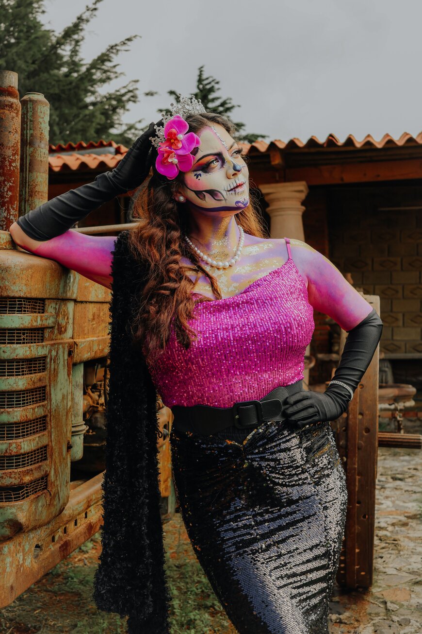 A woman with colorful sugar-skull face makeup and a sequin top for a statement Halloween costume.