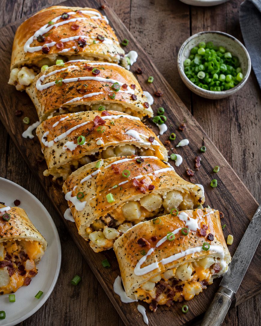 Sliced loaded baked potato stromboli drizzled with sour cream and chives.