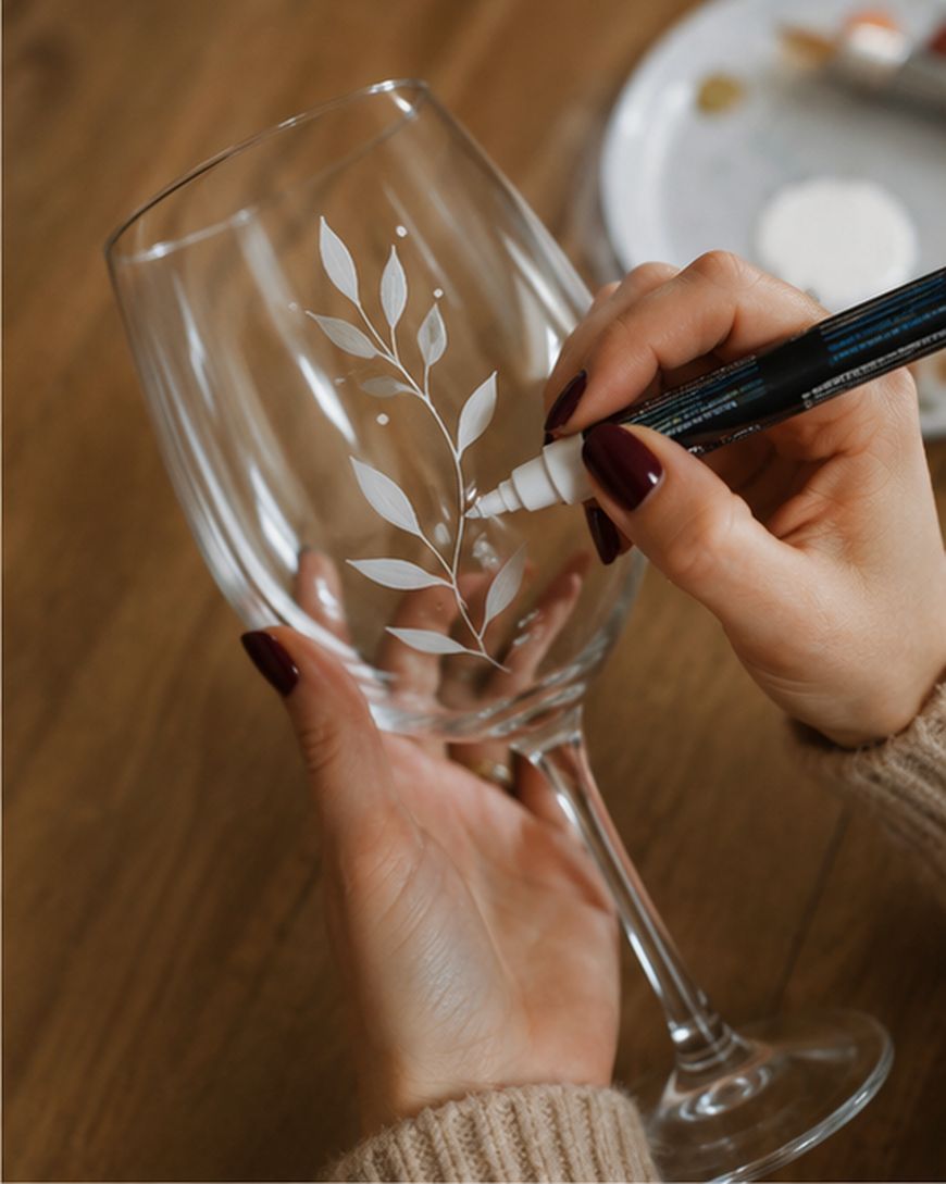 Hand painting a leaf design on a wine glass