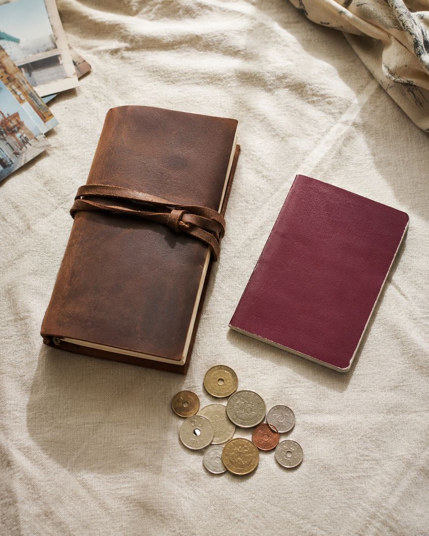 Travel journal, passport, and coins laid out together