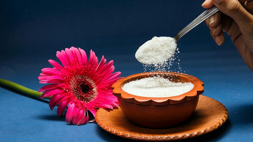 Spoon pouring sugar into a mixing bowl in a baking space