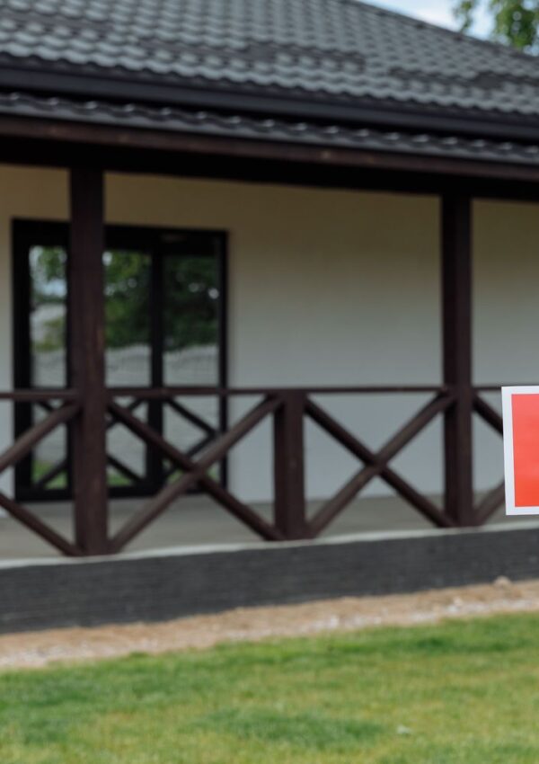 Home for sale sign in front of a house with a covered porch