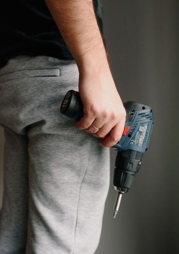 A person holding a cordless power drill, one of the essential tools for working moms managing household projects.