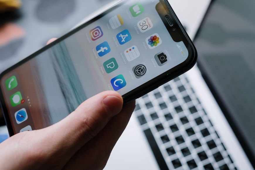 Hand holding a phone showing a home screen of apps for managing household tasks