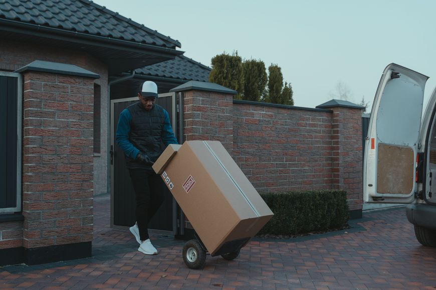 Man delivering a large boxed parcel on a hand truck