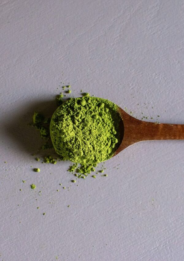 A wooden spoonful of bright green matcha powder.