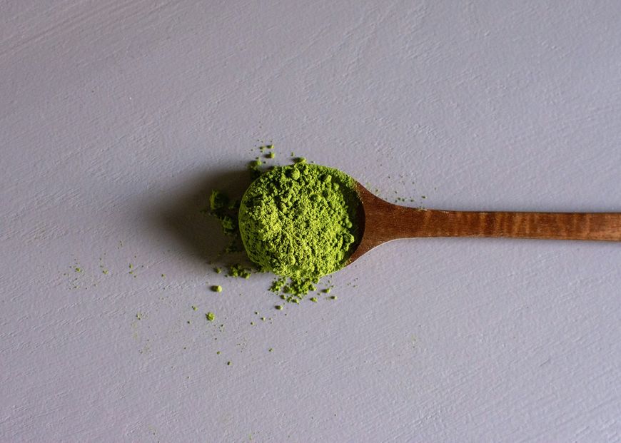A wooden spoon holding a heap of green powder